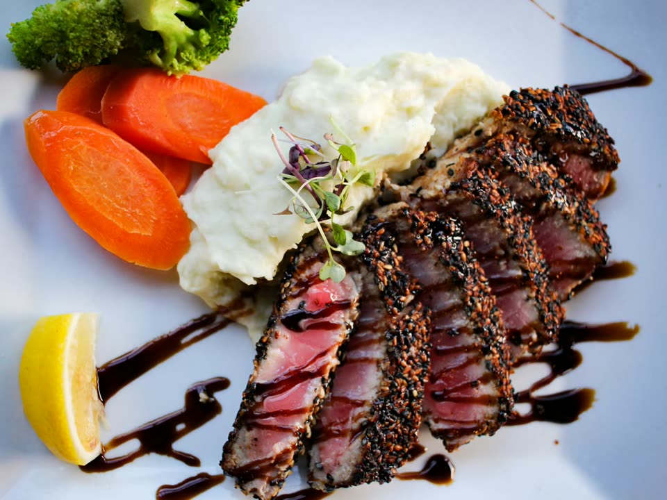 Sesame-seared ahi tuna sliced over vegetables